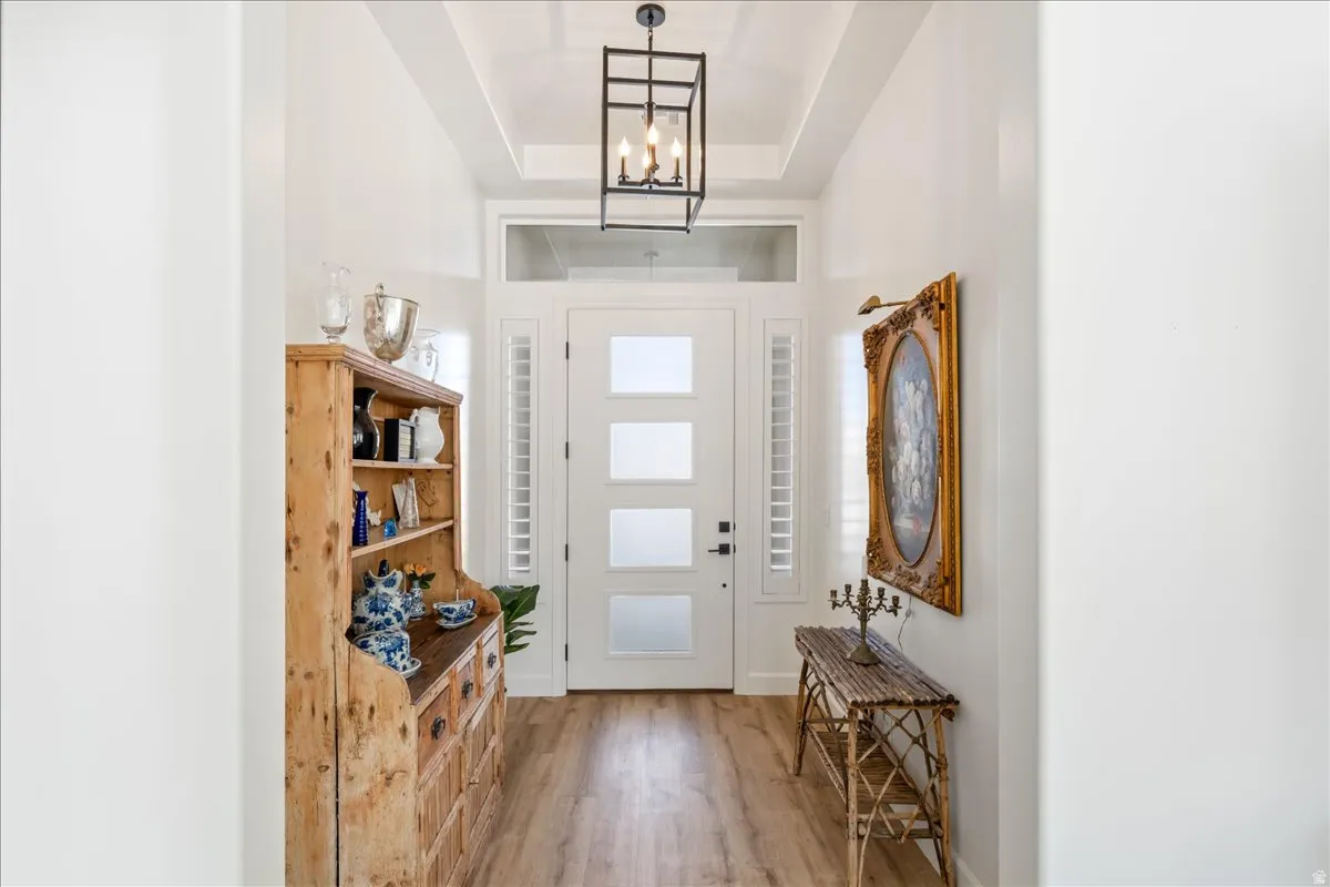 Entrance foyer featuring light wood-style floors, a raised ceiling, and a chandelier