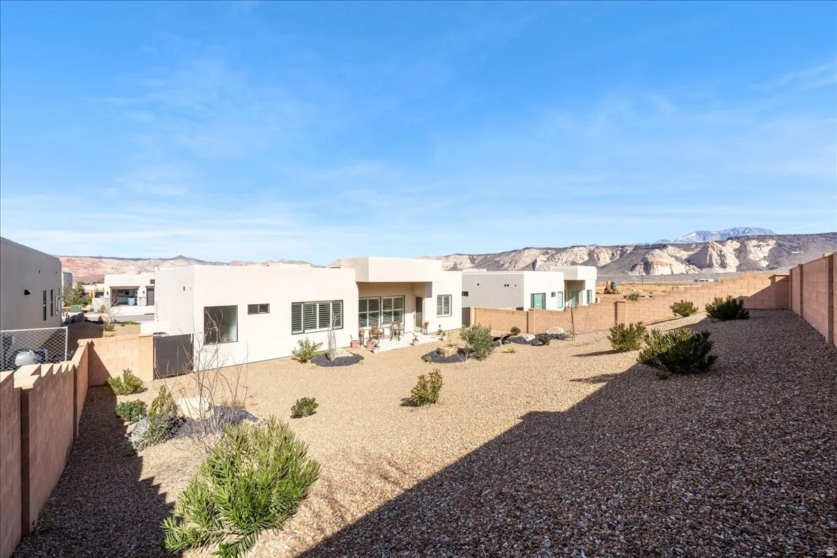Rear view of property with a fenced backyard, a patio area, stucco siding, and a mountain view