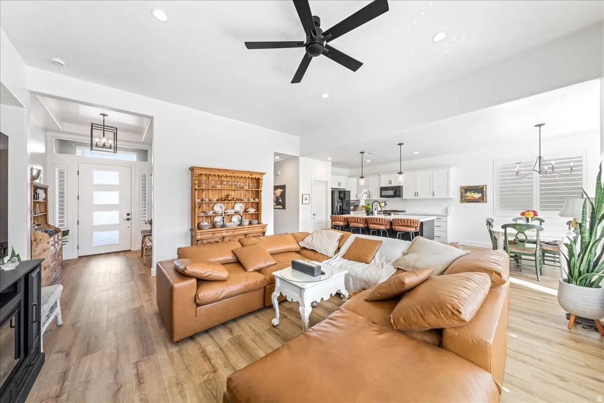 Living room featuring suspended lighting, ceiling fan, and light wood-style flooring