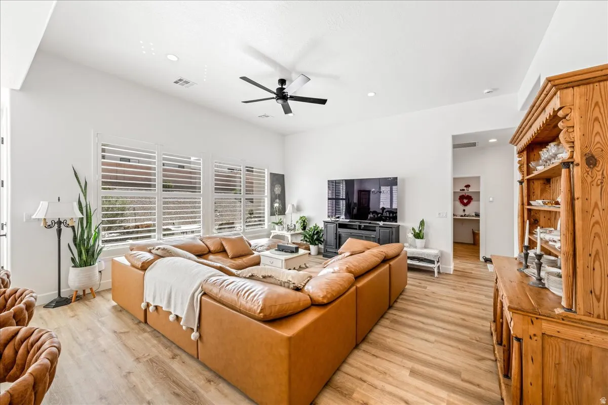Living room with light wood finished floors, a ceiling fan, and recessed lighting