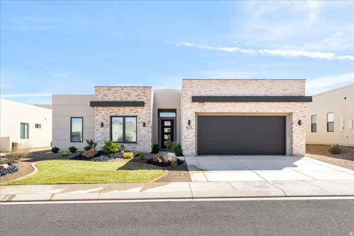 Contemporary home featuring driveway, an attached garage, stone siding, and stucco siding