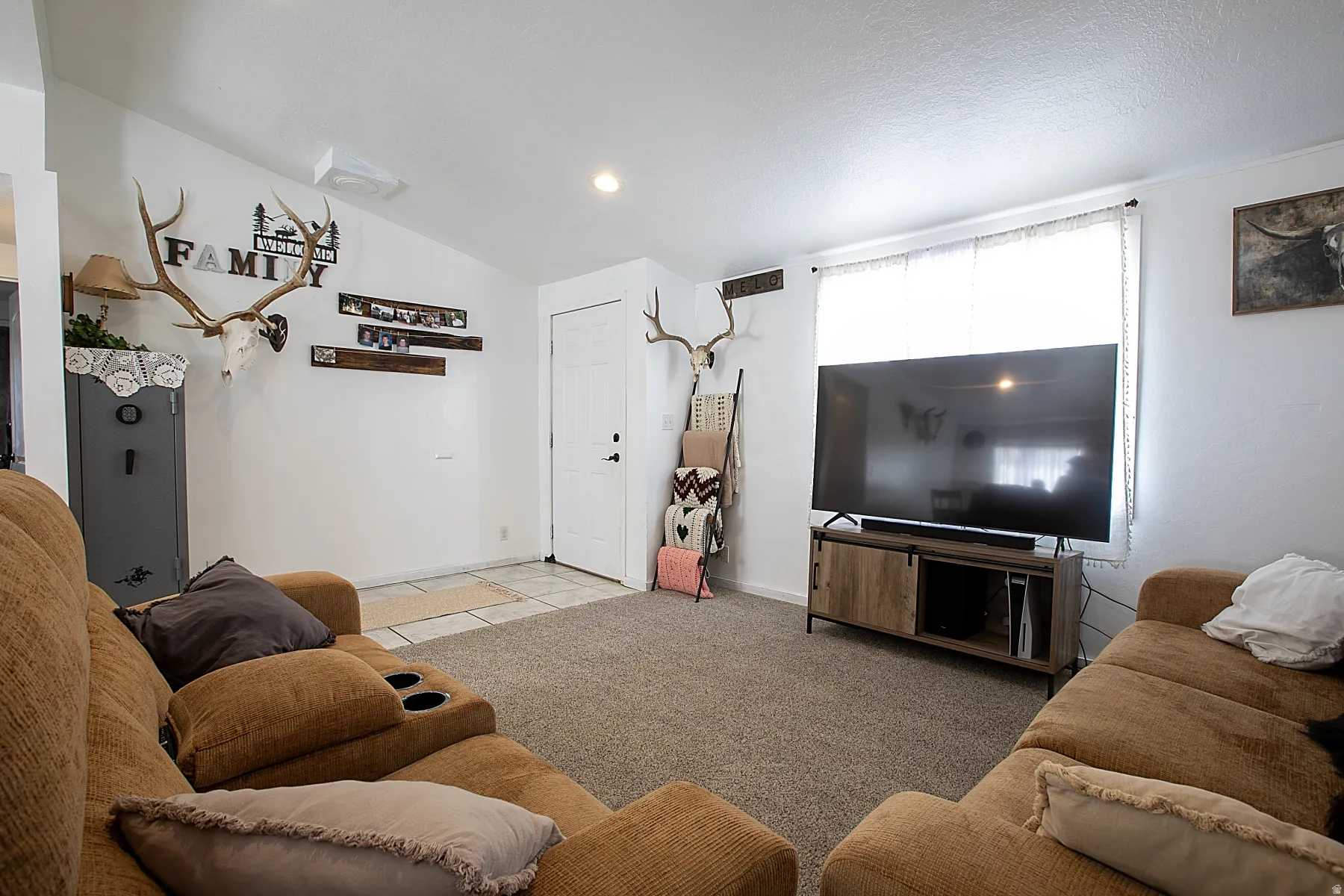 Living area featuring vaulted ceiling, light colored carpet, recessed lighting, and light tile patterned floors