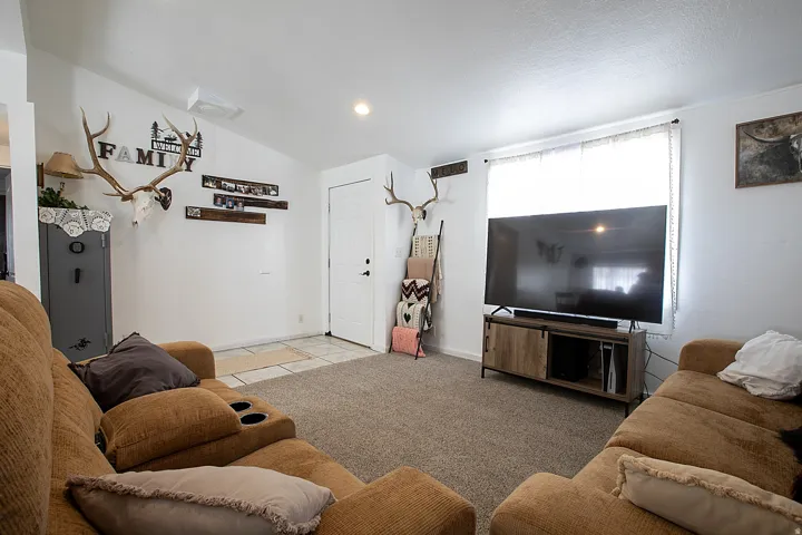 Living area featuring vaulted ceiling, light colored carpet, recessed lighting, and light tile patterned floors