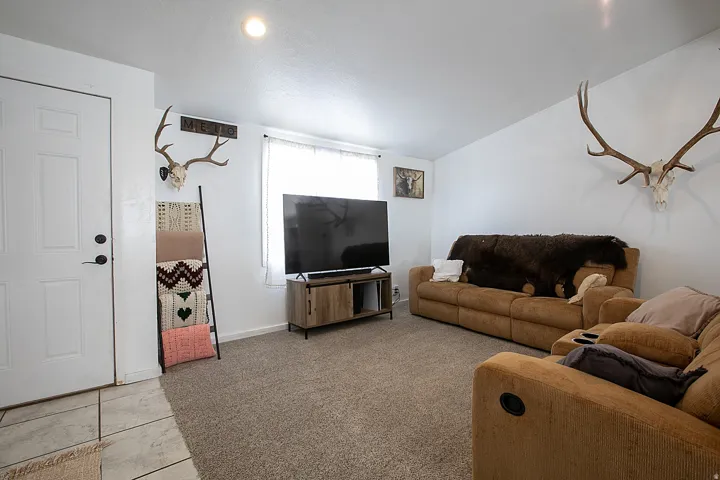 Living room featuring light carpet, light tile patterned floors, and vaulted ceiling