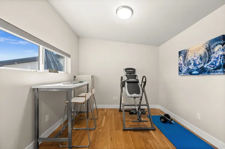 Exercise room with light wood-style floors and baseboards
