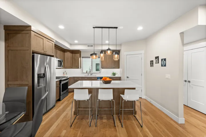 Kitchen featuring stainless steel appliances, a kitchen breakfast bar, light wood finished floors, wood finish cabinetry, and a kitchen island