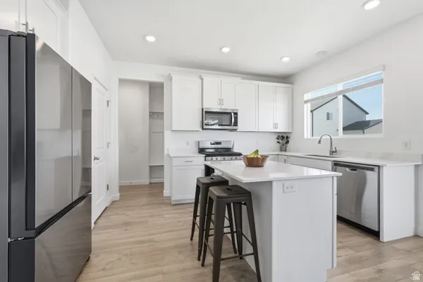 Kitchen featuring stainless steel appliances, white cabinets, and island