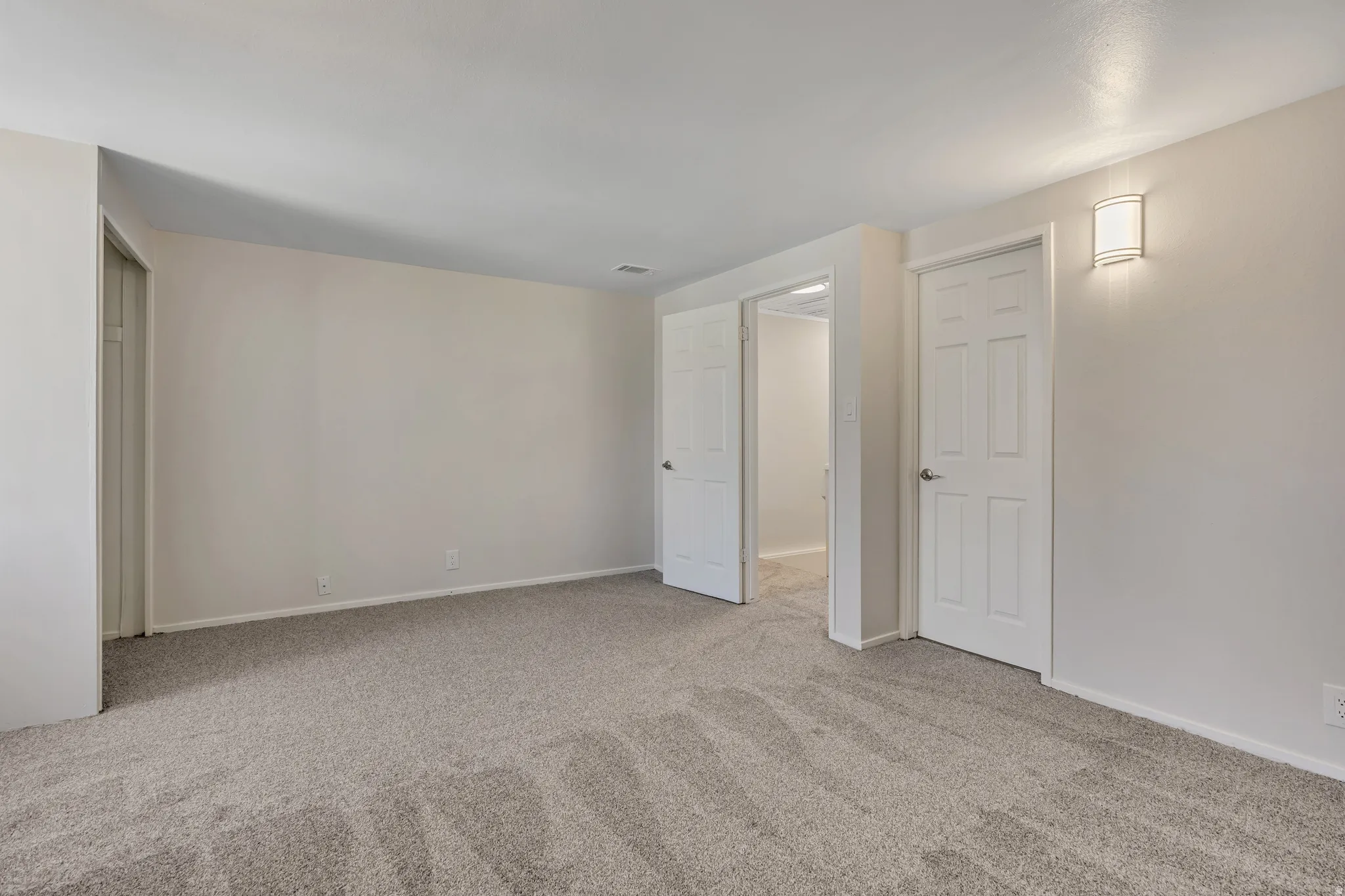 Unfurnished bedroom with light colored carpet and baseboards