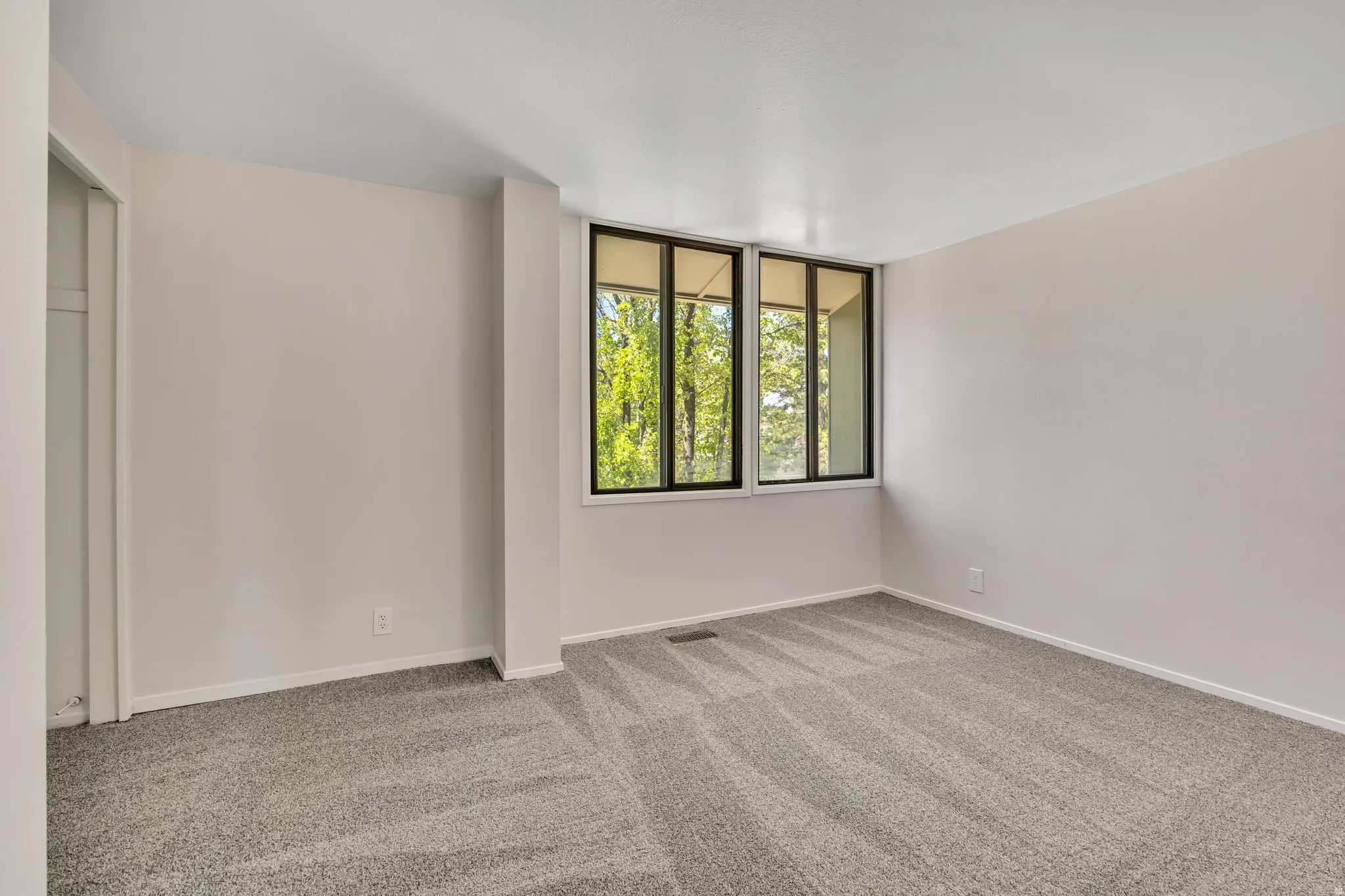 Unfurnished bedroom featuring light carpet and baseboards
