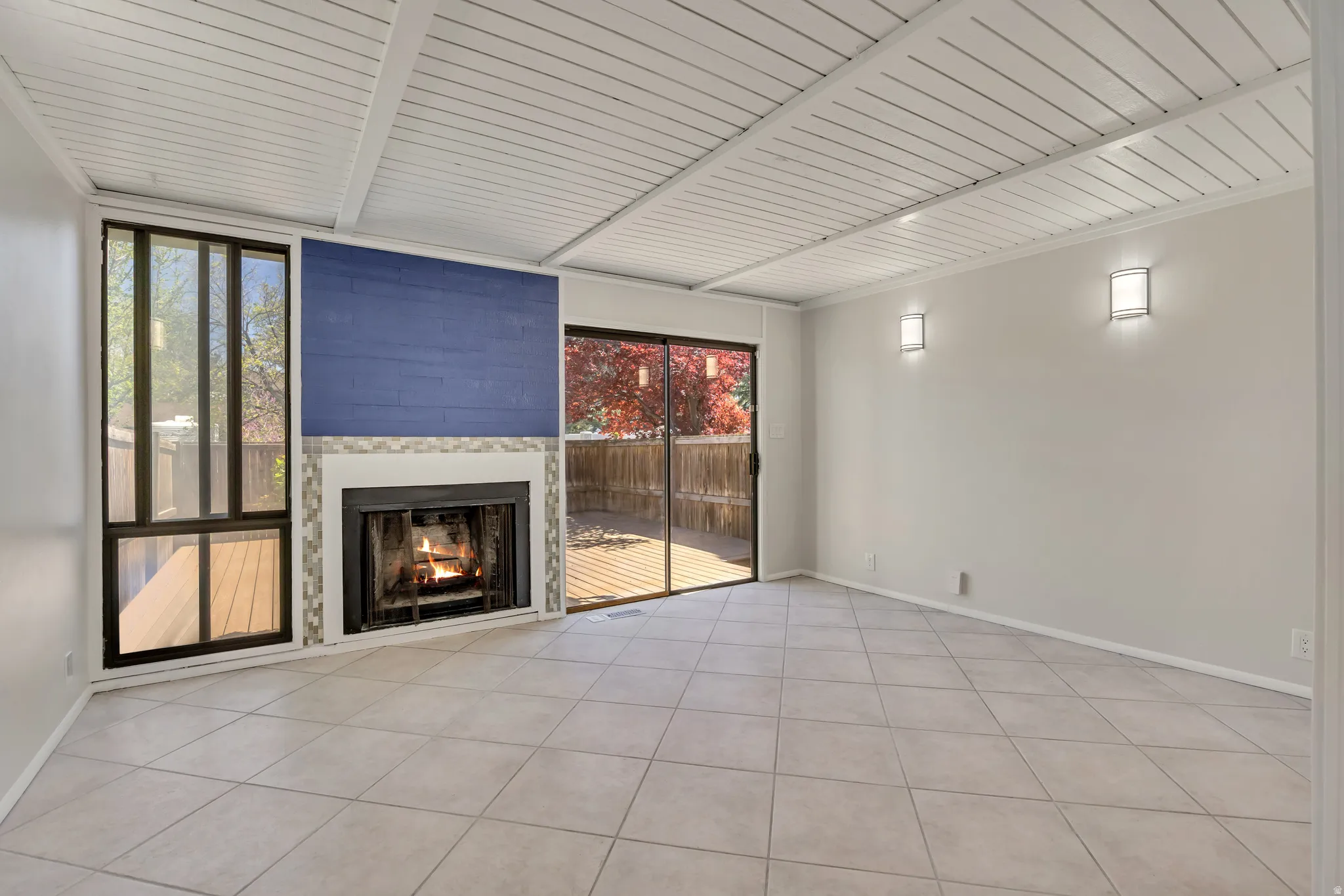 Unfurnished living room featuring a fireplace, light tile patterned flooring, and a wood ceiling with exposed beams