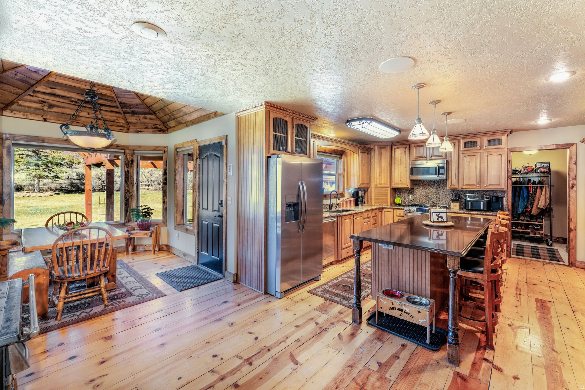 Kitchen featuring pendant lighting, stainless steel appliances, a center island, wood flooring, glass fronted and solid alder cabinets
