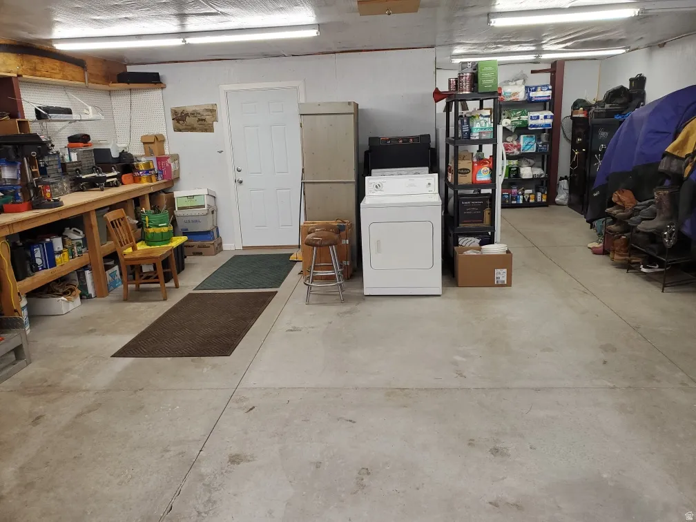 Concrete flooring garage featuring a built-in workbench, fluorescent overhead lighting, and a white paneled door