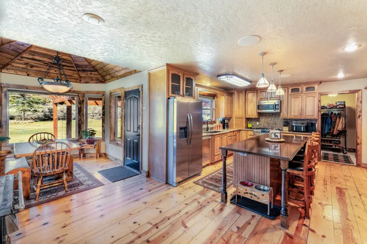 Kitchen featuring pendant lighting, stainless steel appliances, a center island, wood flooring, glass fronted and solid alder cabinets