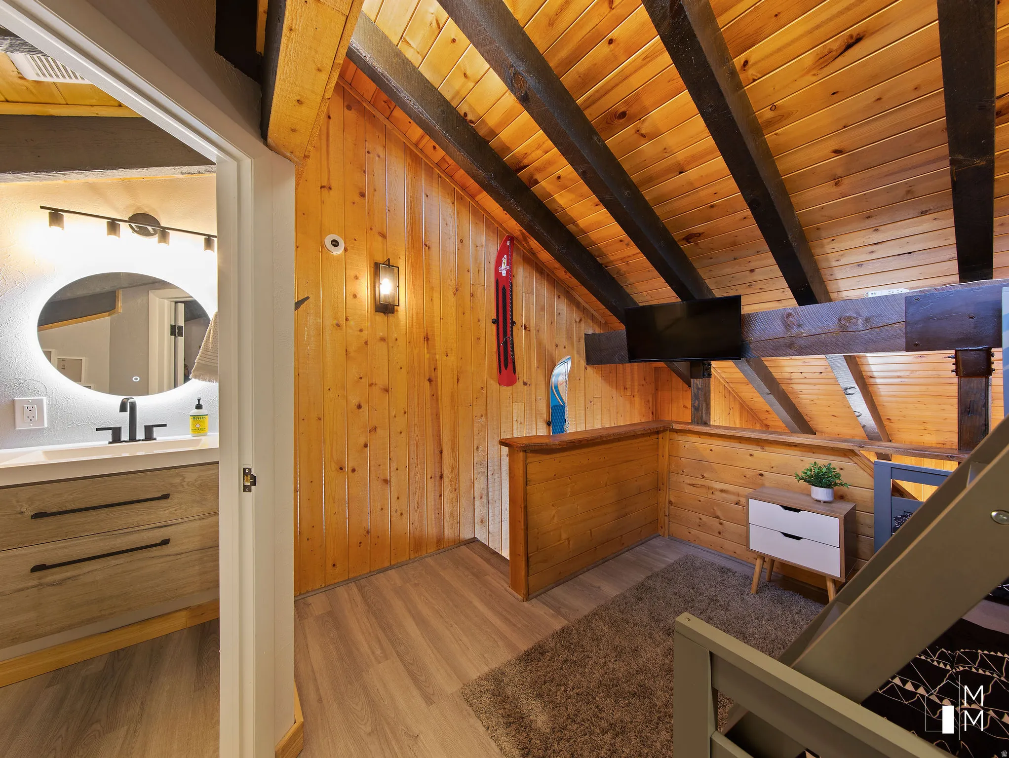 Bedroom with light wood-type flooring, wood walls, and a wooden ceiling with exposed beams