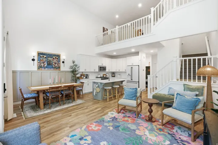 Living room featuring light wood-type flooring, a decorative wall, recessed lighting, and a high ceiling