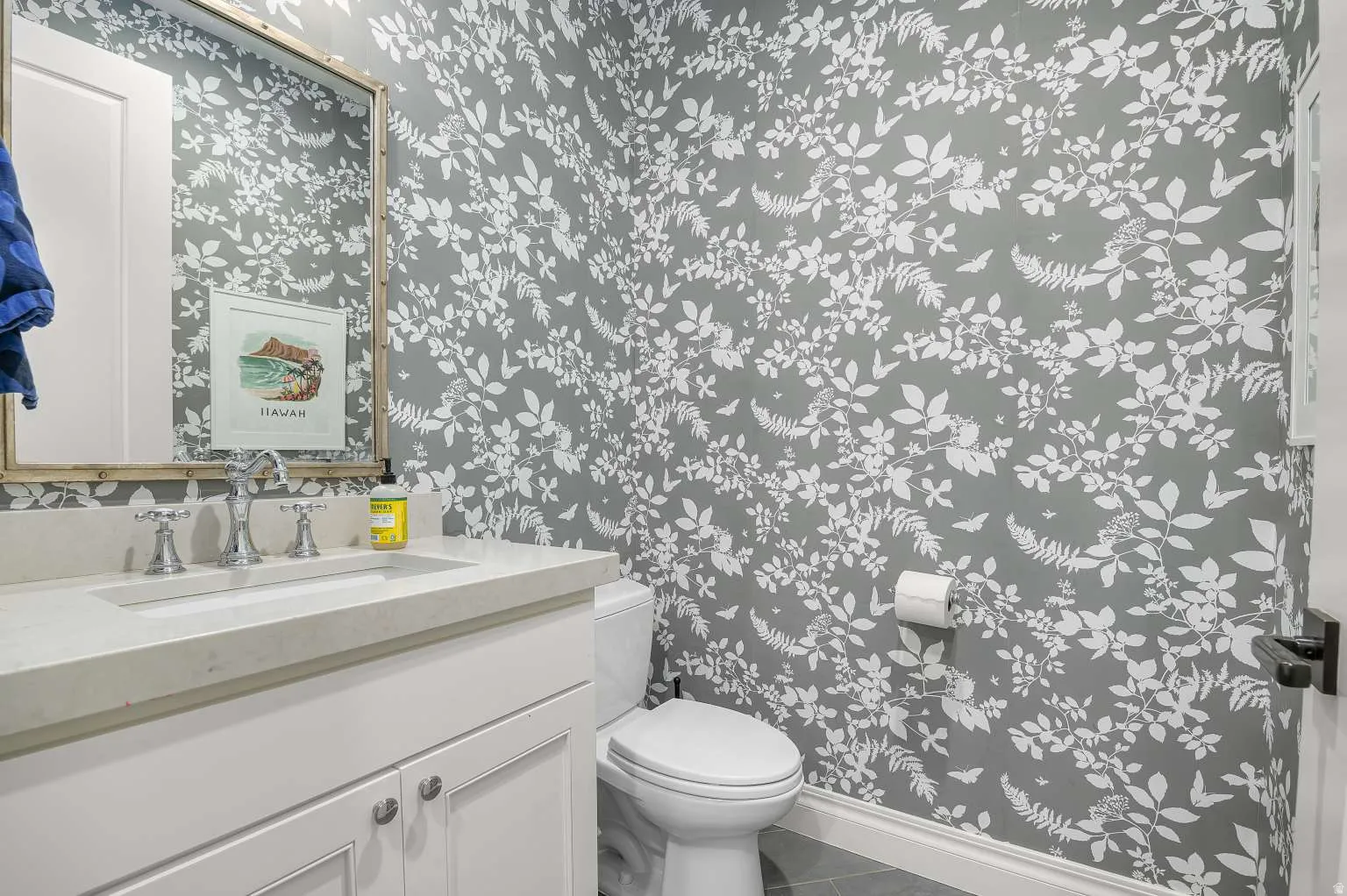 Half bath with wallpapered walls, vanity, and tile patterned flooring