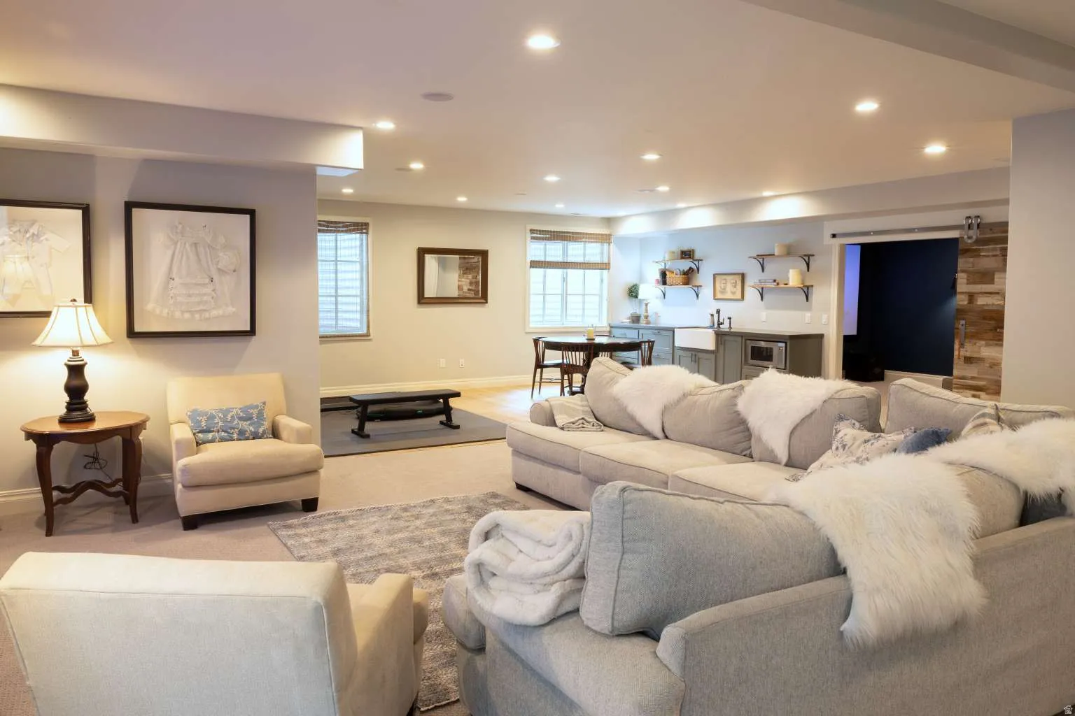 Carpeted living room with a barn door, recessed lighting, and wet bar