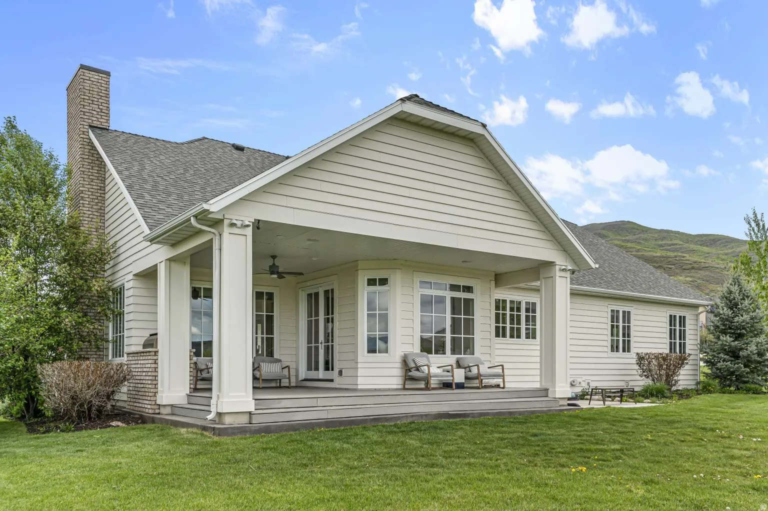 Back of house with ceiling fan, roof with shingles, a yard, a patio area, and a chimney