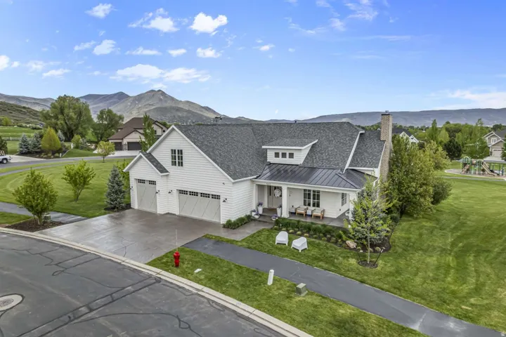 View of front of property featuring covered porch, a standing seam roof, a mountain view, driveway, and a front lawn