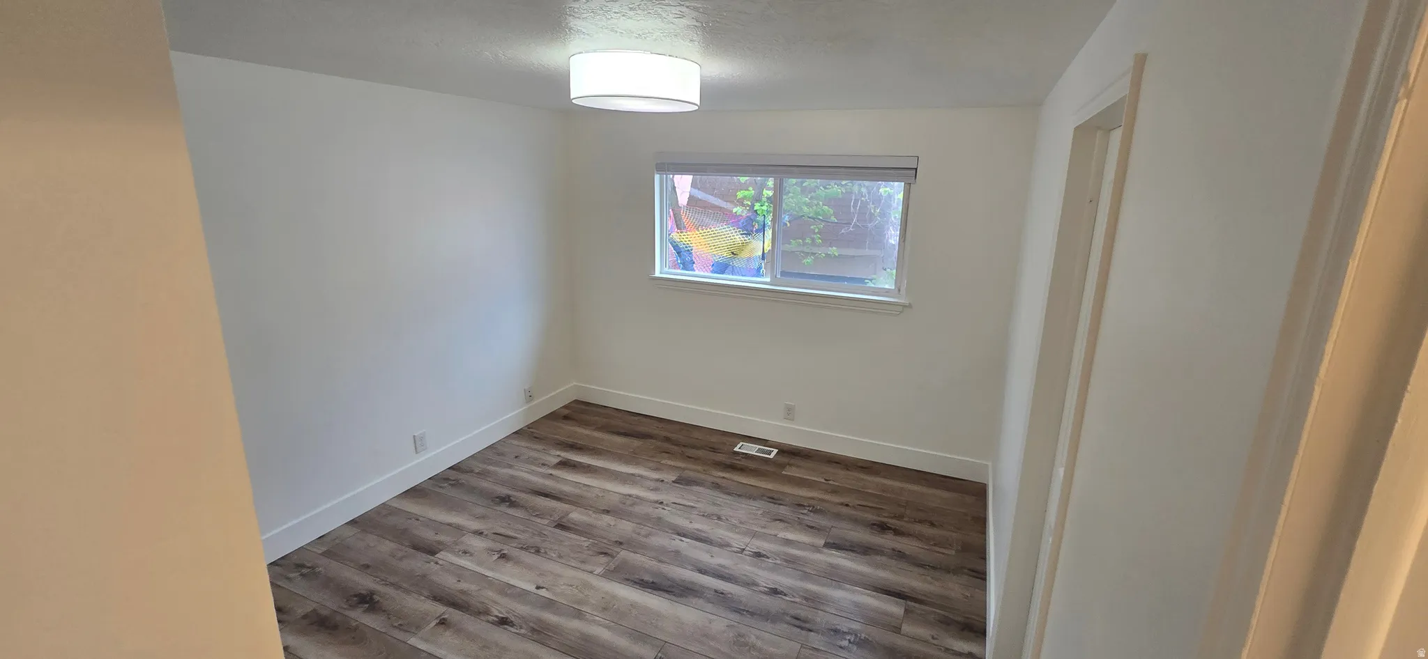 Unfurnished room with wood finished floors and a textured ceiling