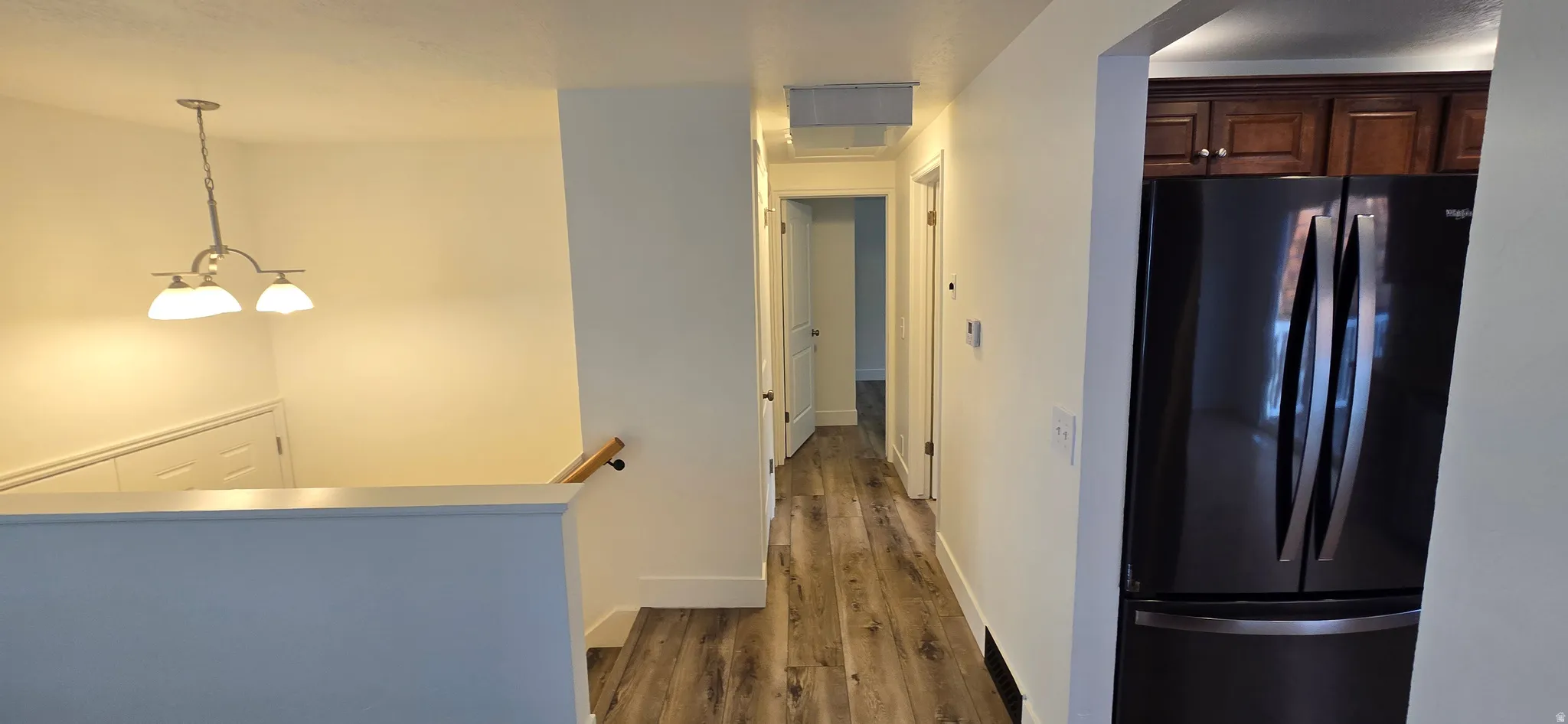 Hallway featuring dark wood-style floors and an upstairs landing