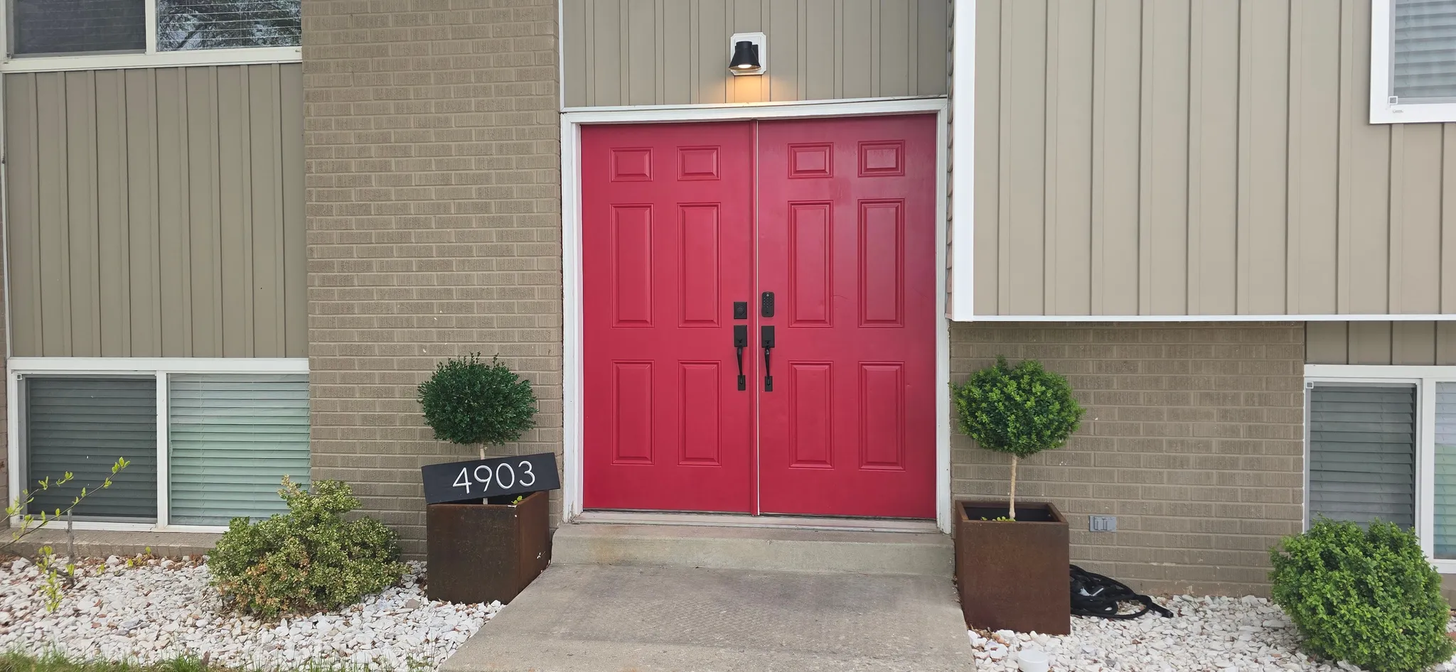 Property entrance featuring board and batten siding and brick siding