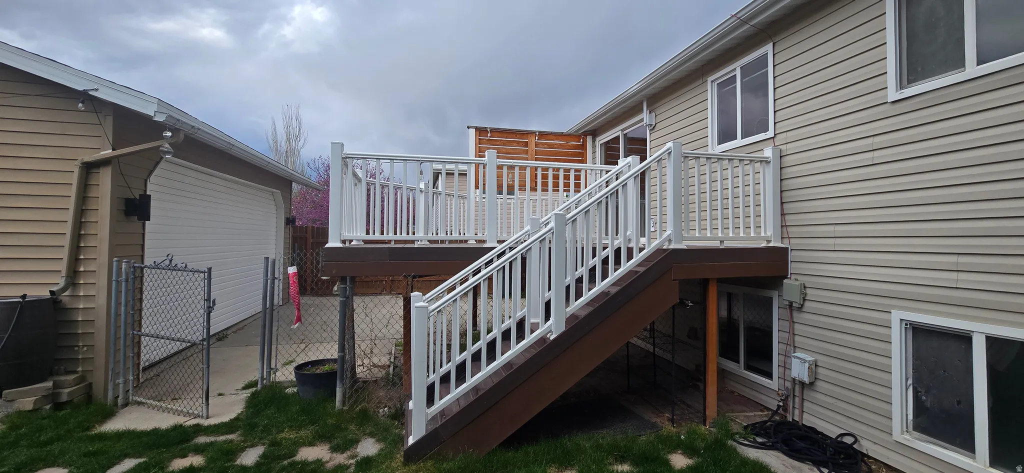 Wooden terrace featuring a gate, a garage, and a patio area