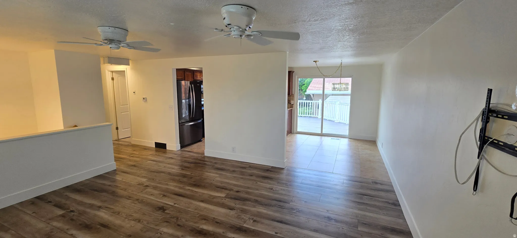 Unfurnished room featuring a textured ceiling, a ceiling fan, and dark wood-style flooring