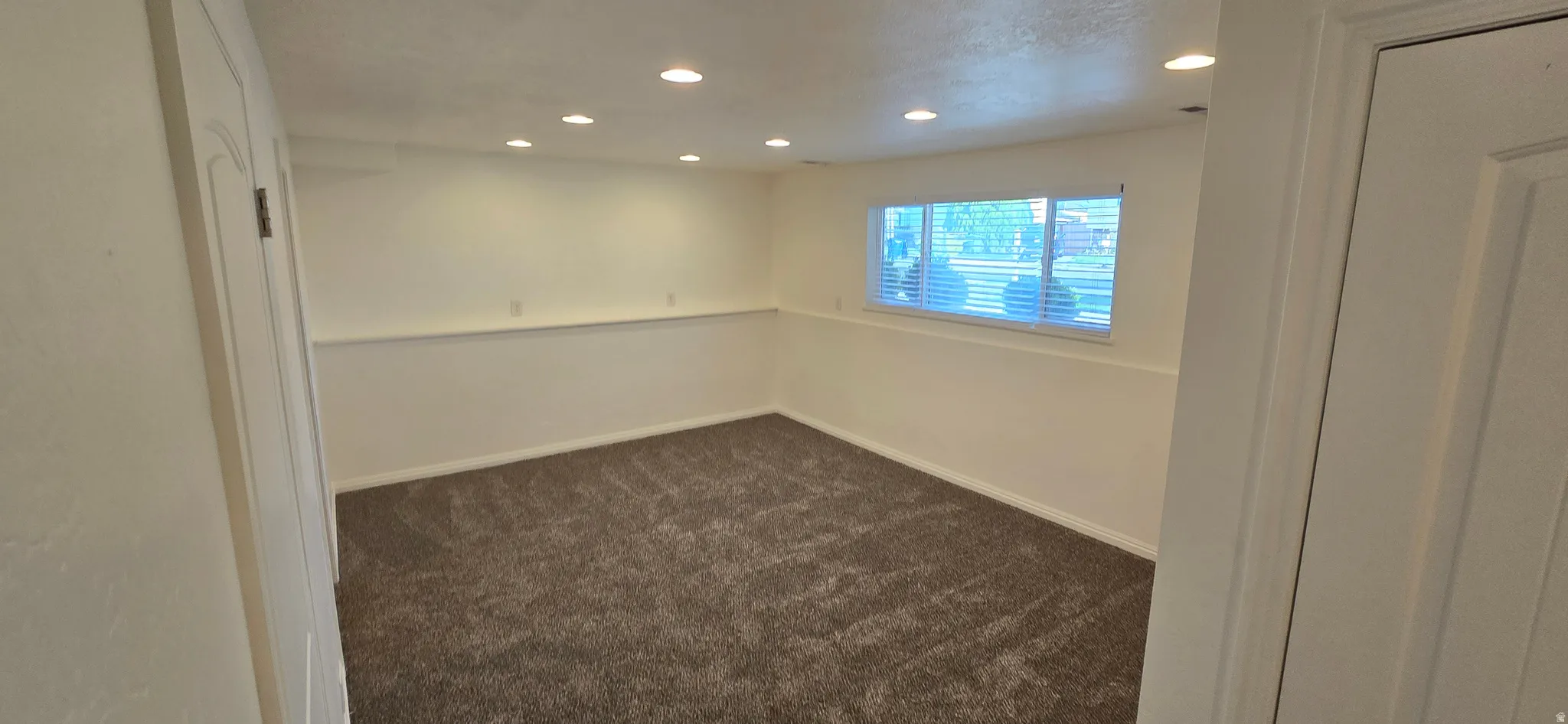 Unfurnished room with recessed lighting and dark colored carpet