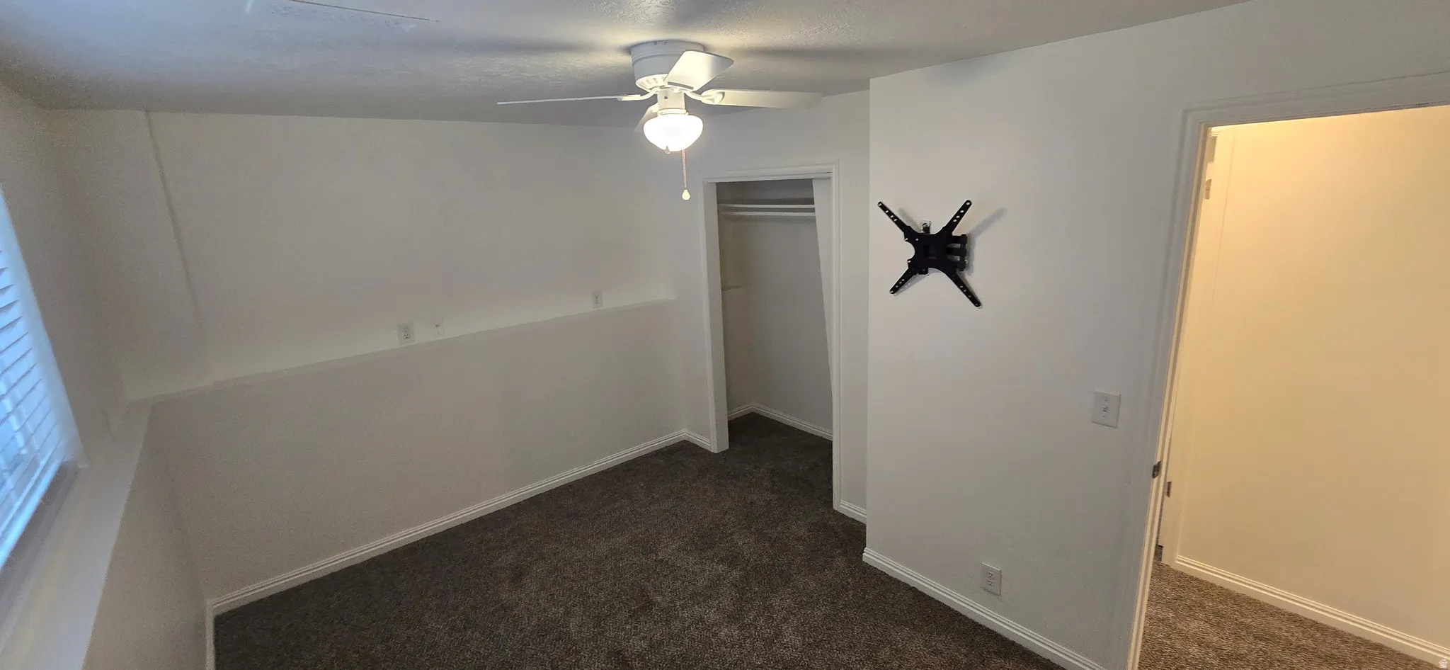 Unfurnished bedroom featuring dark carpet, a ceiling fan, and a closet