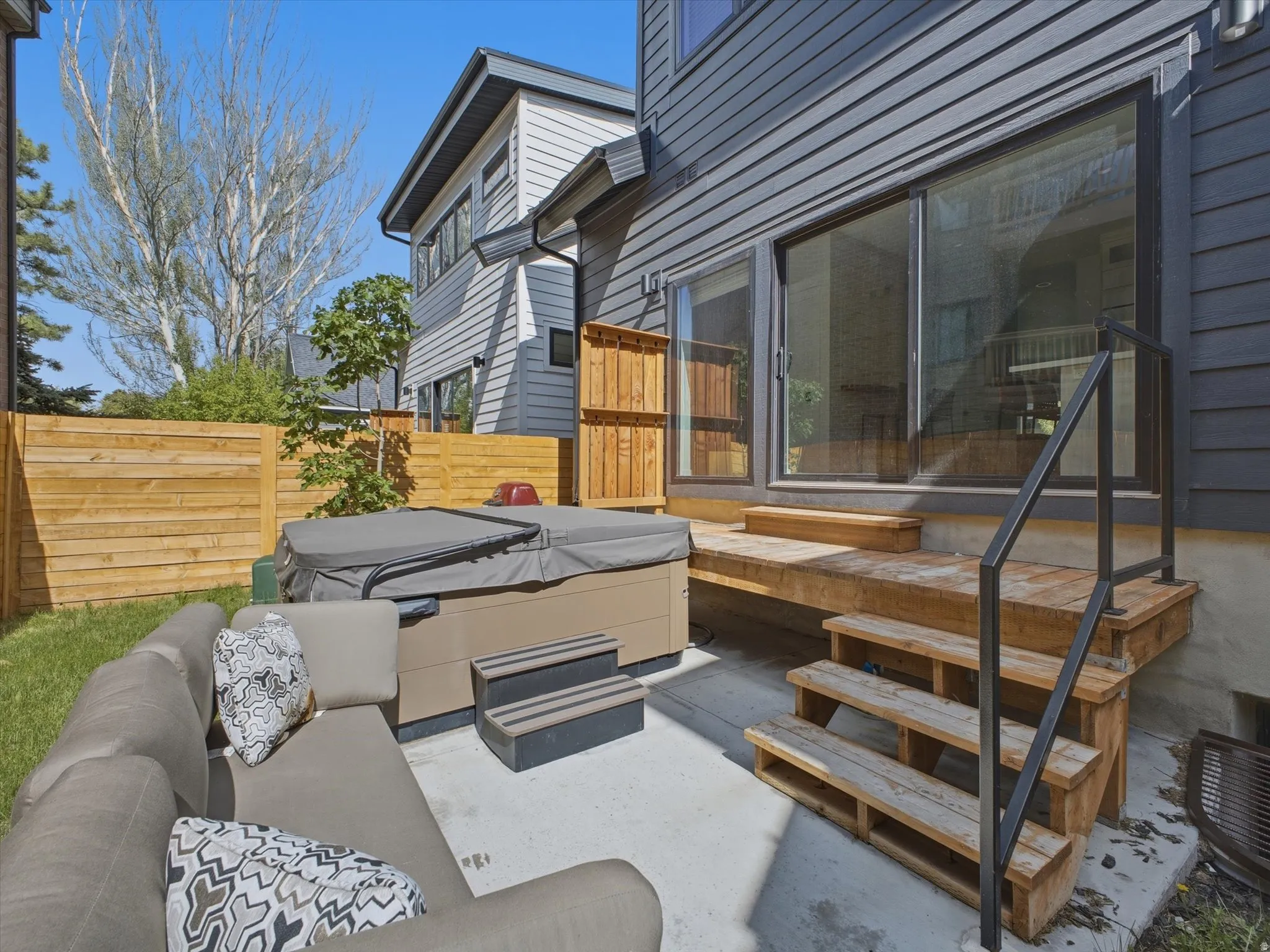 Exterior patio featuring a hot tub, concrete pad, wooden decking, and sliding glass doors
