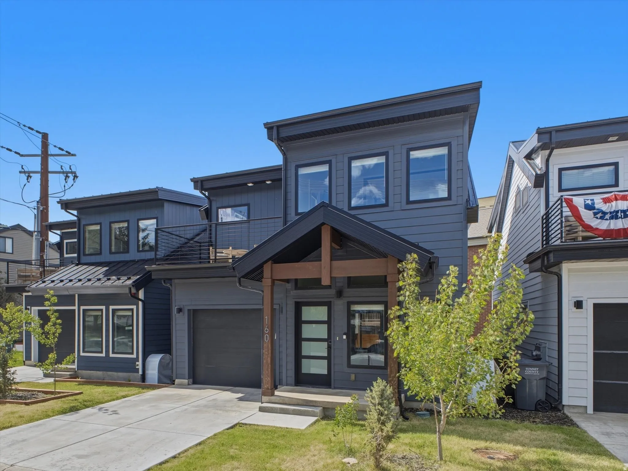 Modern multi-story facade featuring dark grey siding and black-framed windows