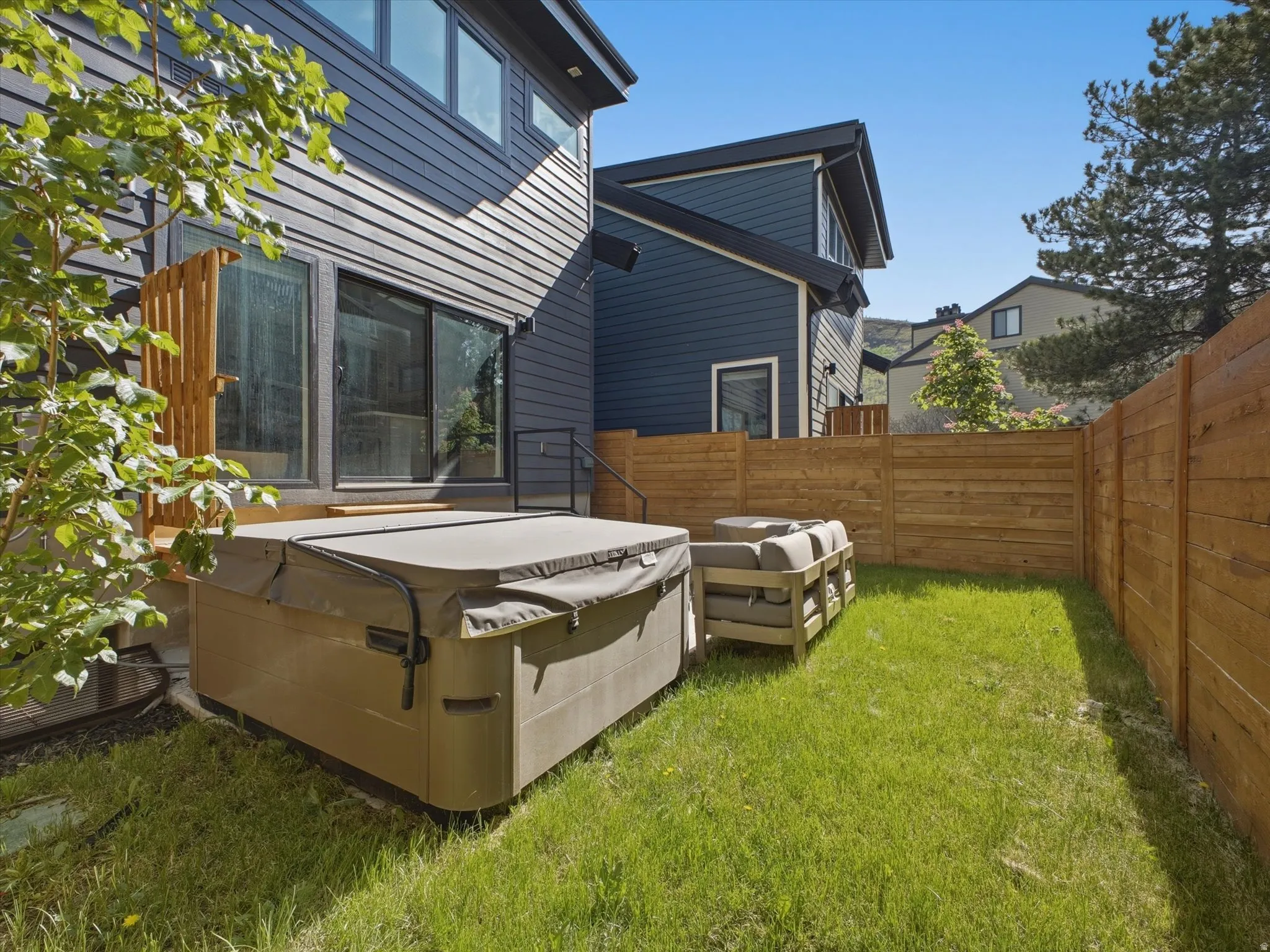 Private backyard featuring a hot tub, a manicured lawn, and a wooden privacy fence