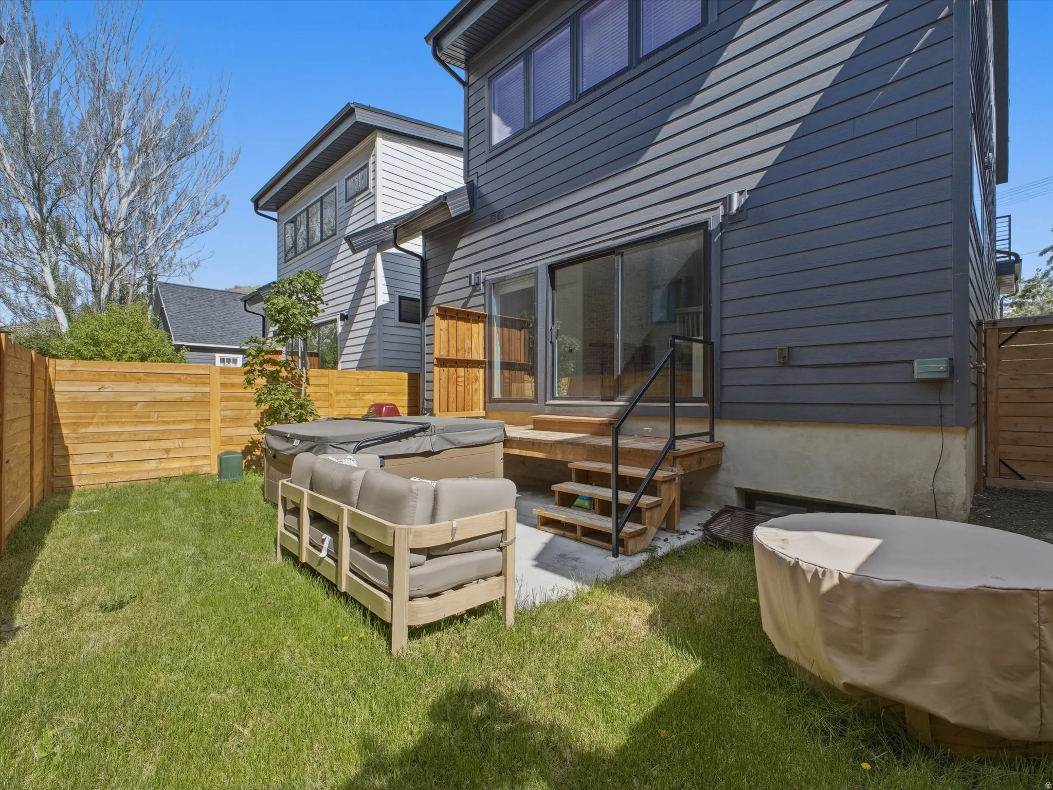 Private backyard with a manicured lawn, full-height privacy fencing, and a built-in wood deck with stairs and a metal railing