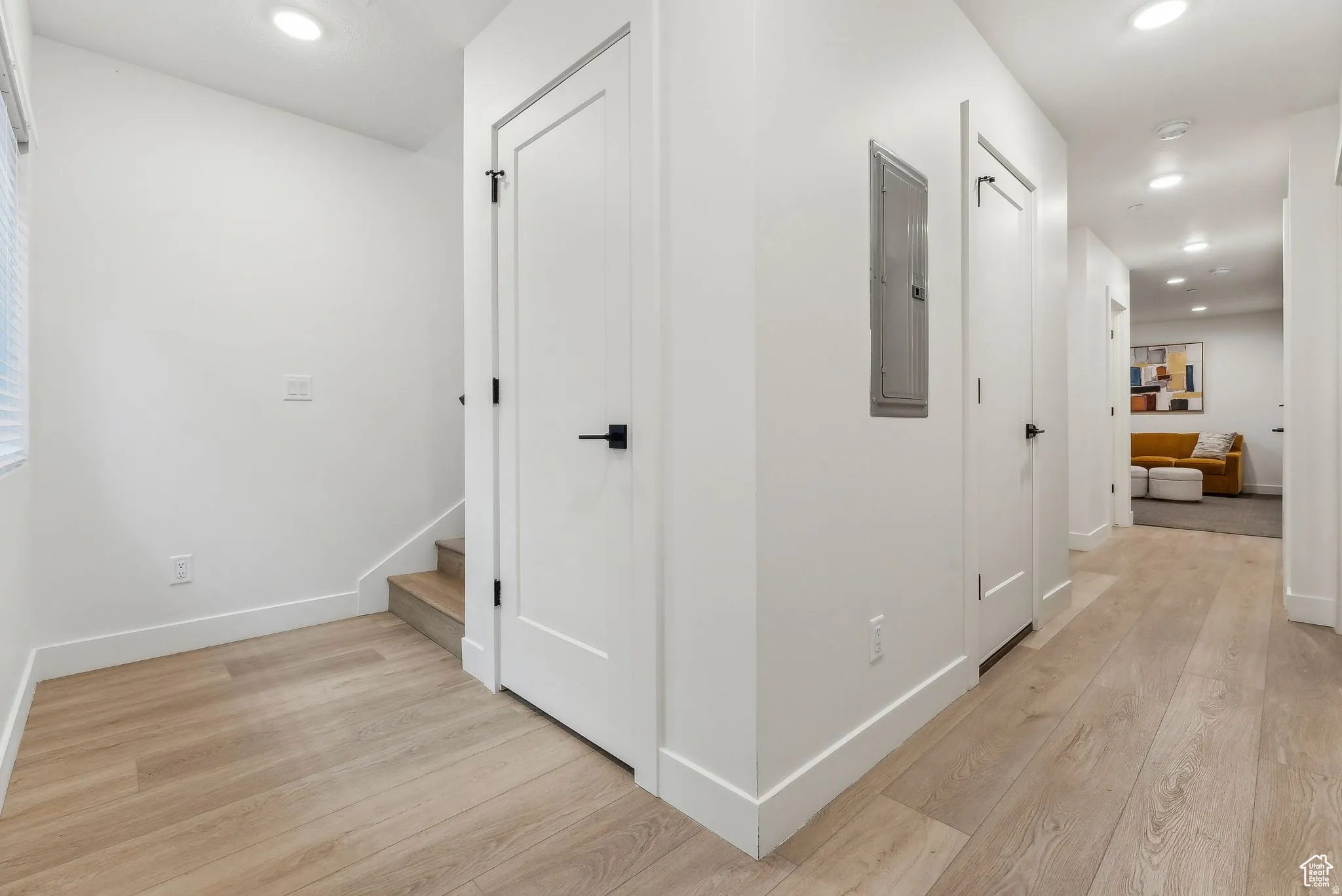 Hall with recessed lighting, light wood-style floors, and electric panel