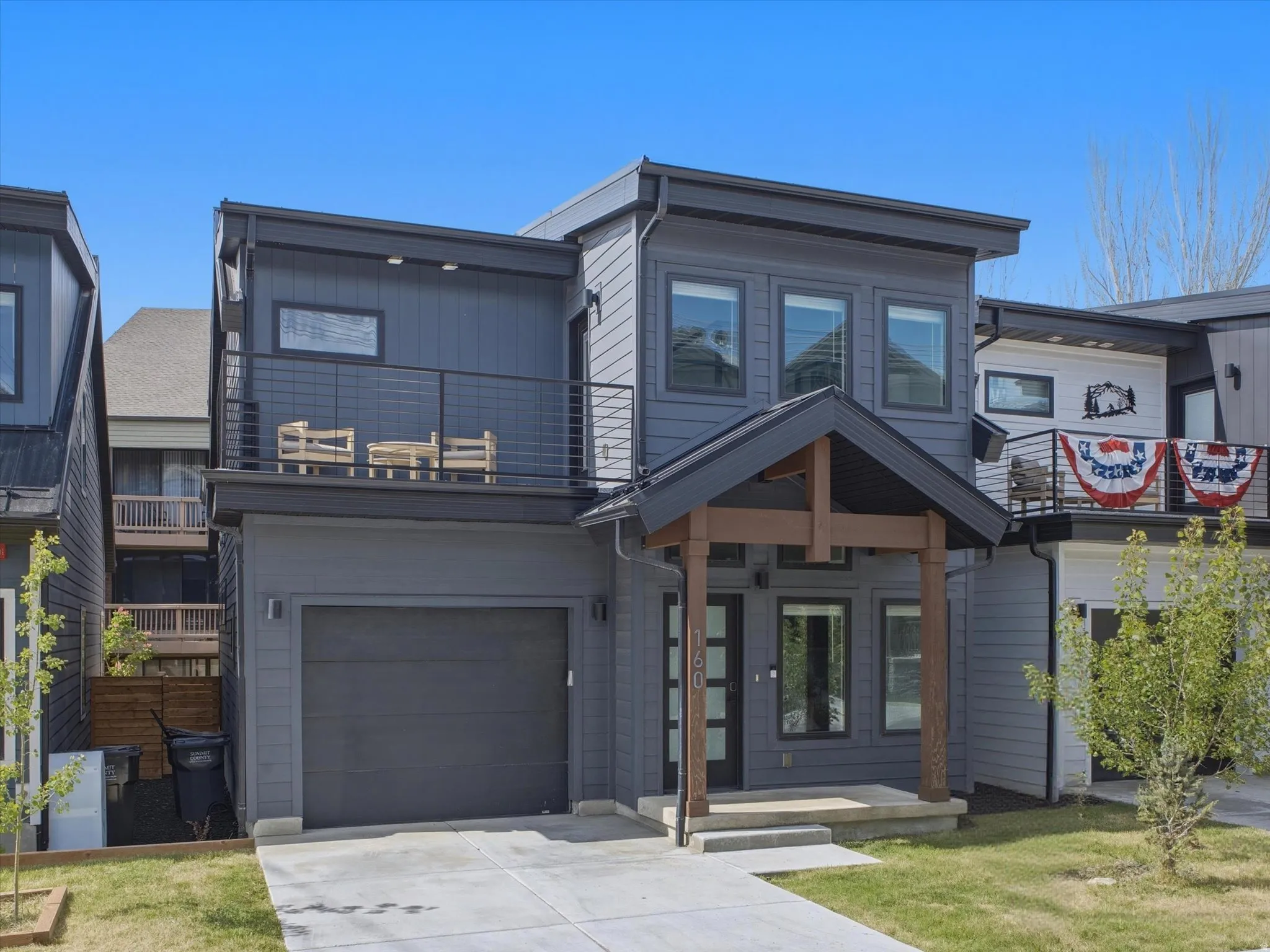 Modern-style home featuring dark gray siding and a covered entry with wood-toned columns