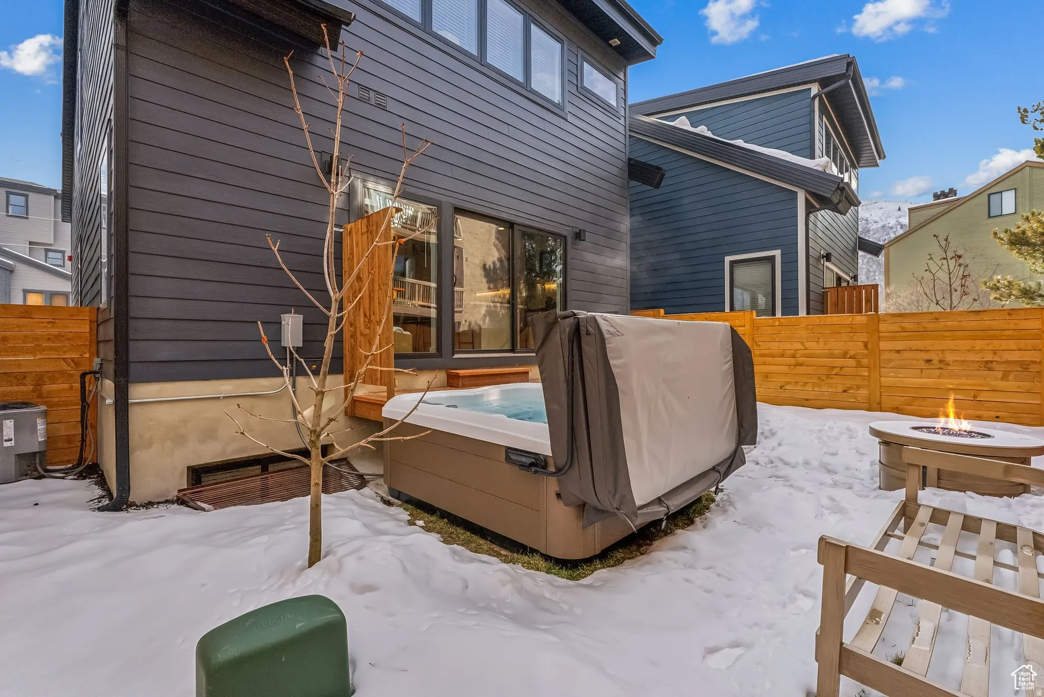 Snow covered house with a fire pit and a hot tub