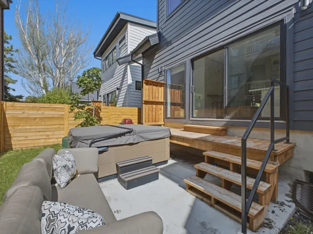 Exterior patio featuring a hot tub, concrete pad, wooden decking, and sliding glass doors