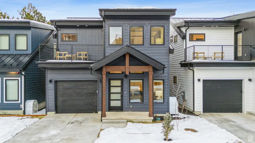 View of front of property featuring concrete driveway, a balcony, and a garage