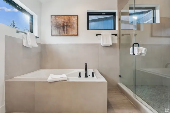 Full bathroom featuring a garden tub, a stall shower, and light wood-style floors