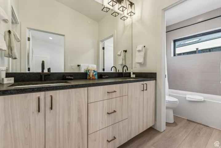 Bathroom with double vanity, light wood-style floors, and bathtub / shower combination