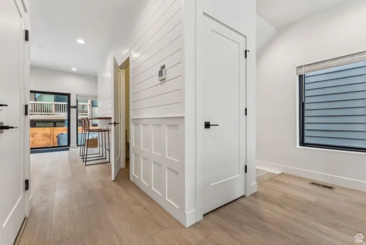 Hallway with light wood-type flooring and recessed lighting