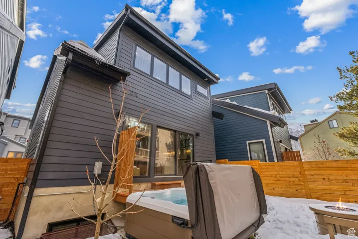 Rear view of property featuring a fire pit and a hot tub