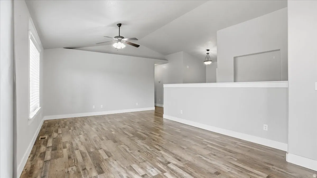 Spare room with vaulted ceiling, ceiling fan, and light wood-style flooring