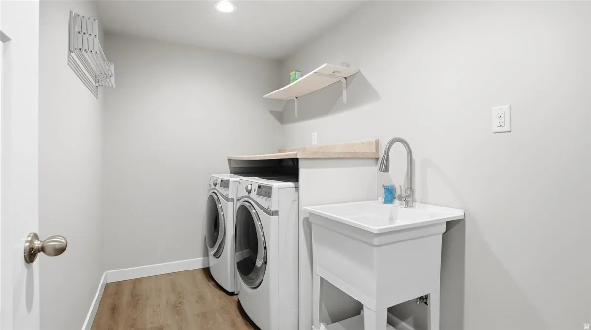 Laundry room featuring light wood-style floors, separate washer and dryer, and recessed lighting