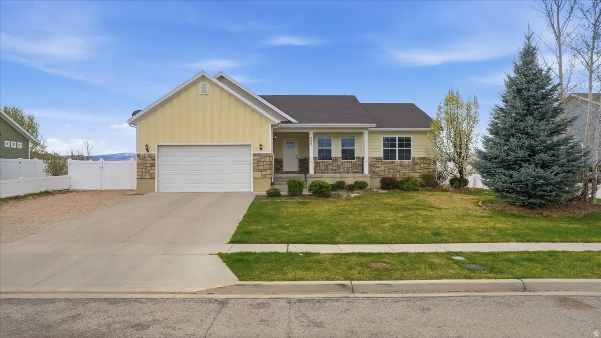 View of front of home with covered porch, board and batten siding, a gate, a garage, and stone siding