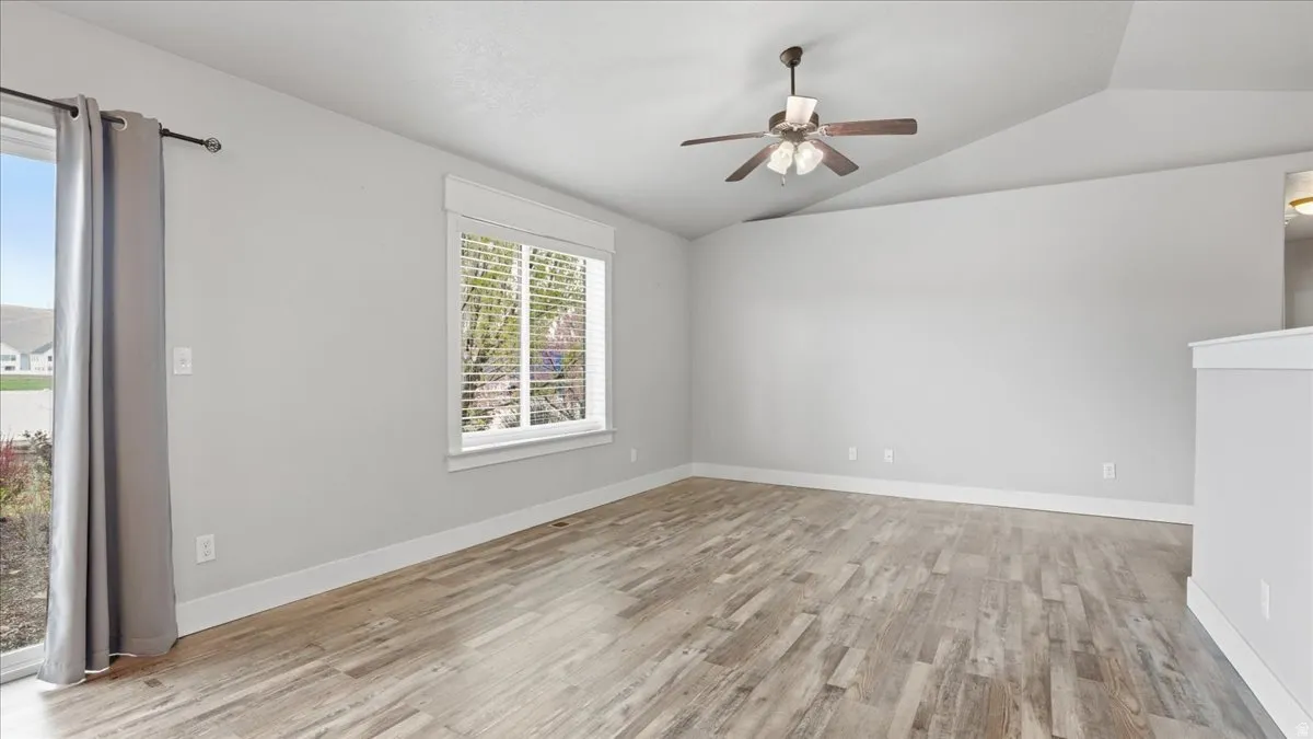 Spare room with light wood-style floors, lofted ceiling, and a ceiling fan