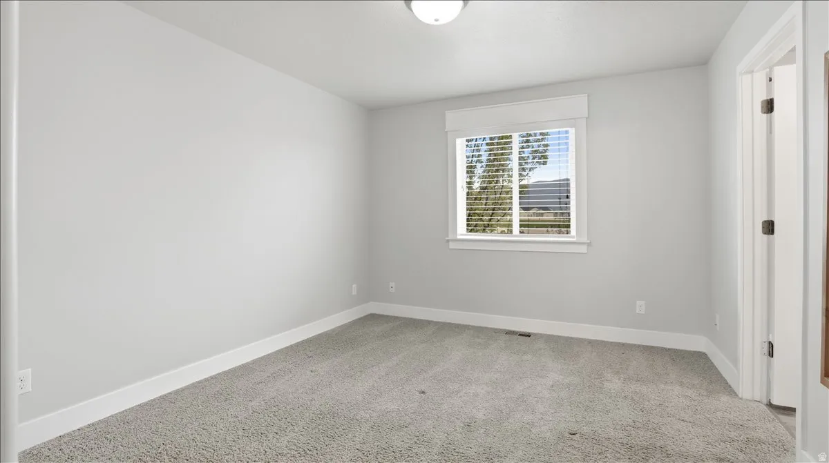Primary bedroom with baseboards and light colored carpet