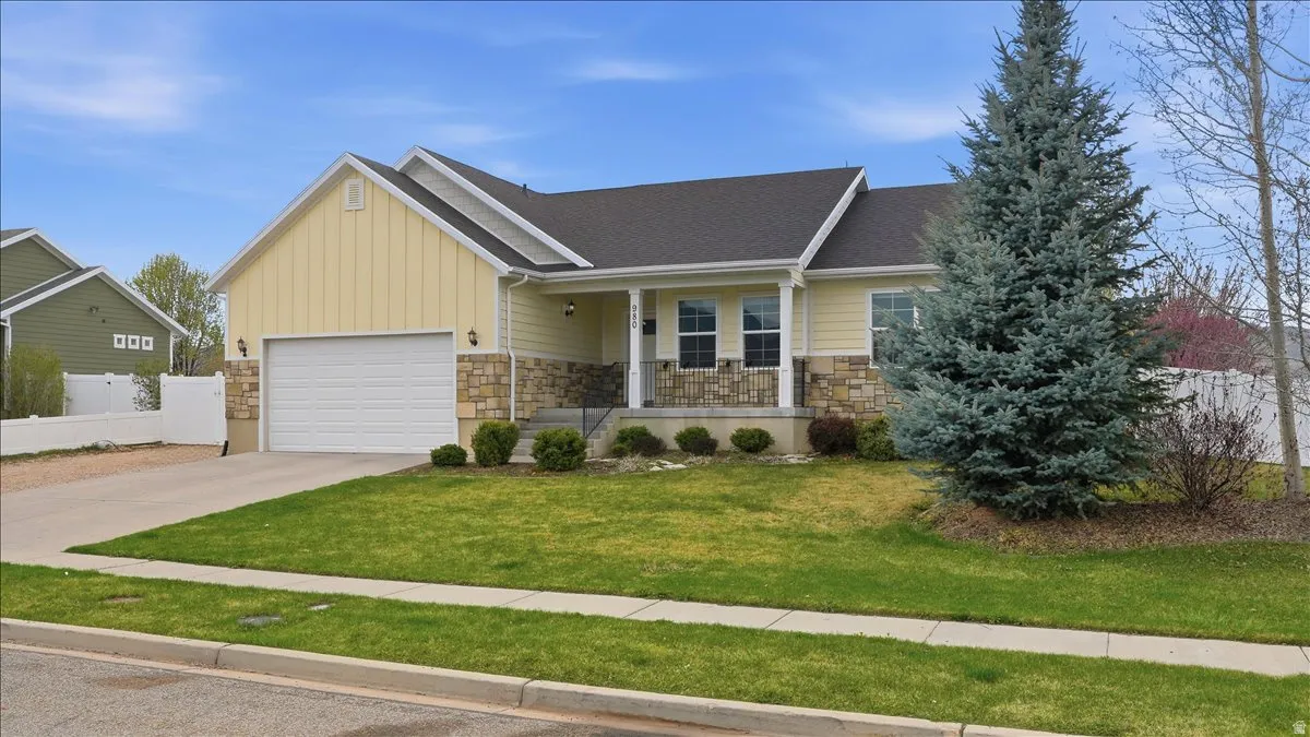 View of front of house featuring stone siding, a porch, board and batten siding, a garage, and concrete driveway