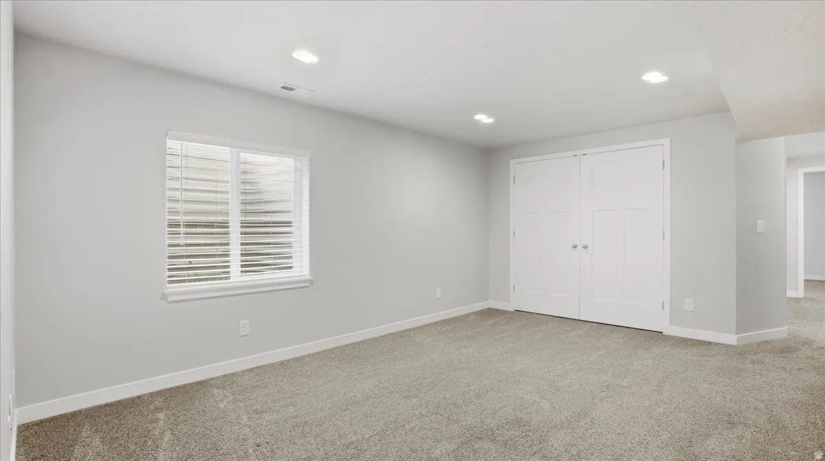 Unfurnished bedroom with light carpet, a closet, and recessed lighting